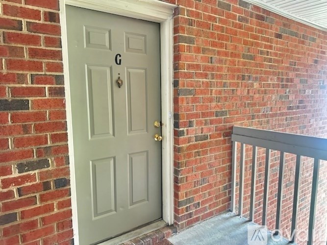 A grey door with a gold handle is on a brick wall.