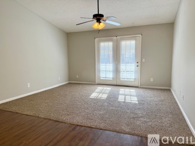 A room with a carpeted floor, a ceiling fan, and a sliding glass door.