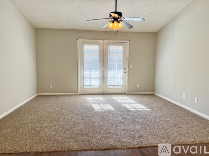 A room with a carpeted floor and a ceiling fan.