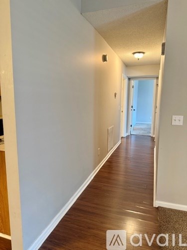 A hallway with wood flooring and white walls.