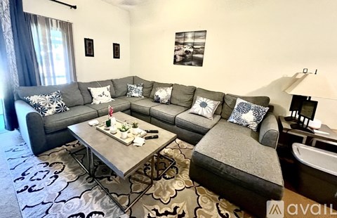 A living room with a grey sofa, a grey armchair, a grey coffee table, and a rug with a pattern.