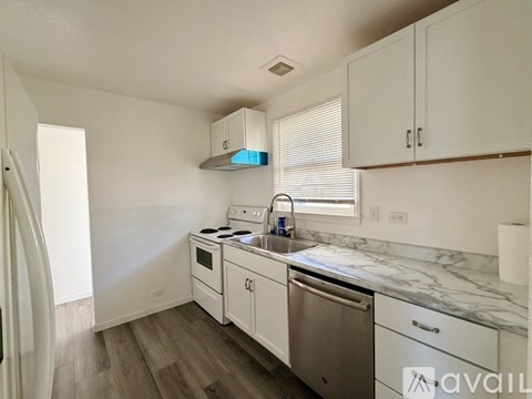 A kitchen with white cabinets and a marble countertop.