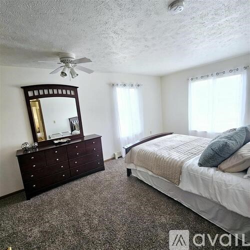 A bedroom with a bed, dresser, and mirror.