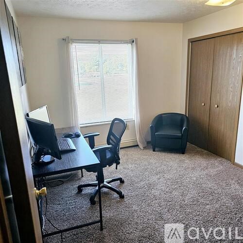 A room with a desk, chairs, and a carpeted floor.