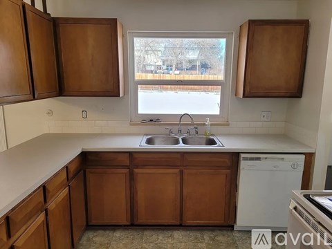 A kitchen with wooden cabinets and a window overlooking a street.