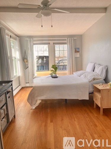 A bedroom with a bed, a ceiling fan, and a wooden floor.