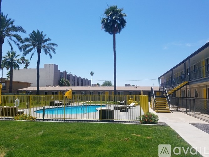 A pool surrounded by palm trees and a yellow fence.