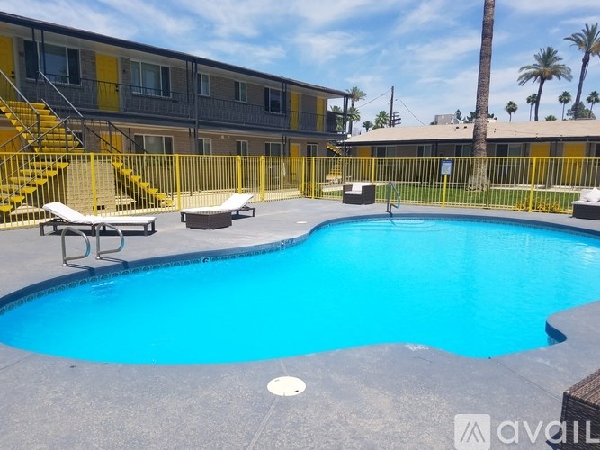 A pool surrounded by a yellow fence and a building in the background.