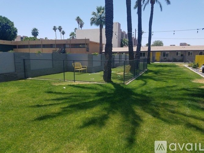 A sunny day at the park with a yellow chair and a fence.