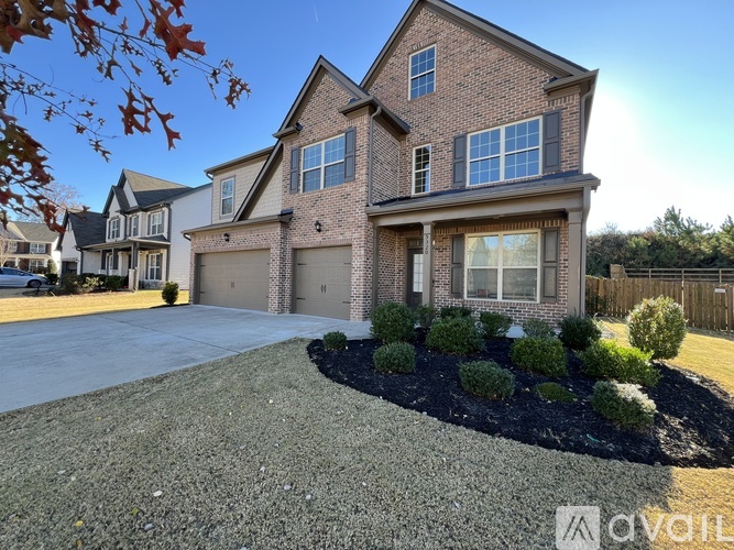 A large brick house with a driveway and a landscaped front yard.
