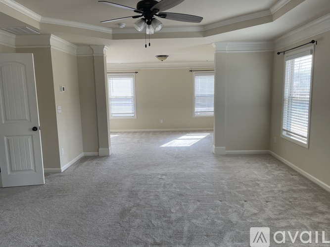 A spacious room with a ceiling fan and carpeted floor.