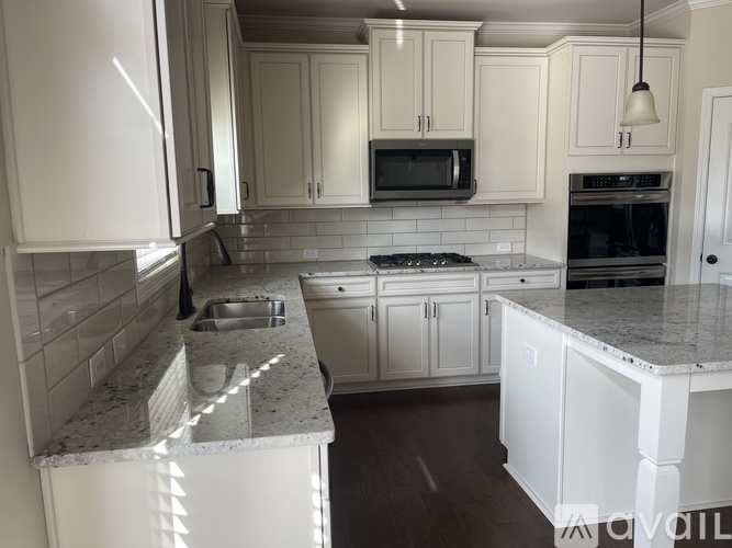 A kitchen with white cabinets and a marble countertop.