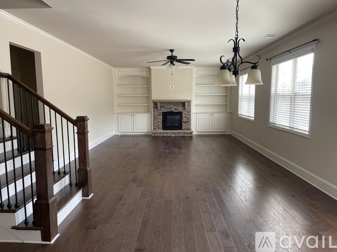 A spacious living room with wood flooring and a fireplace.