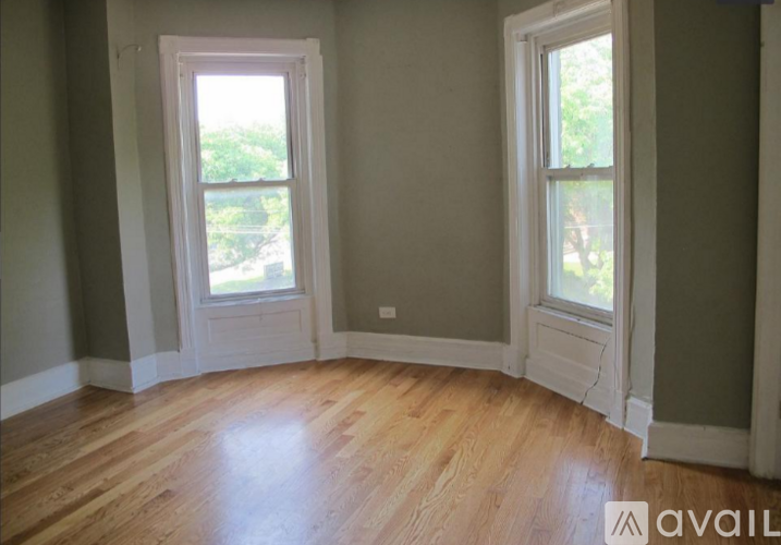 A room with two windows and wooden floors.