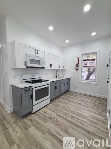 A kitchen with white cabinets and a wooden floor.