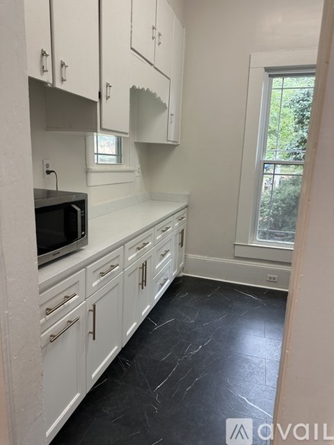 A kitchen with white cabinets and a black countertop.