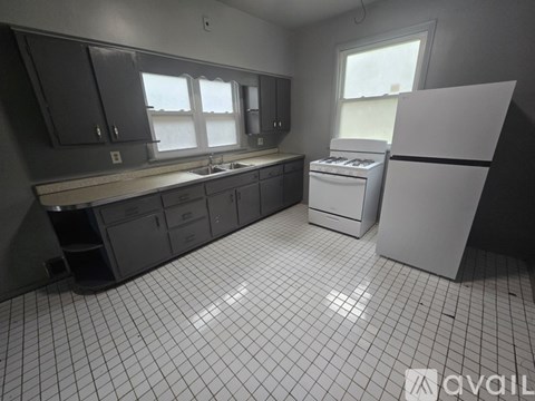 A kitchen with a white fridge, sink, and cabinets.