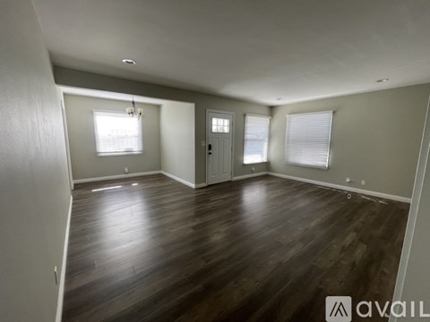 A spacious room with wooden flooring and white walls.