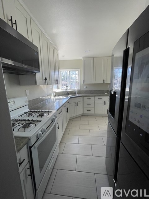 A kitchen with white cabinets and a black fridge.