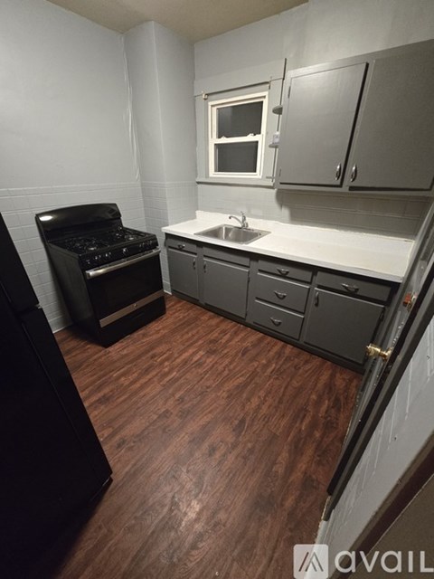 A kitchen with a black stove and wooden floors.