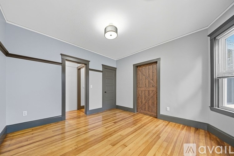 A room with wooden floors and a window on the right side.
