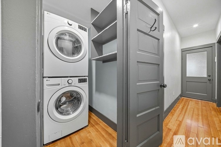 A washer and dryer are stacked on top of each other in a small room.