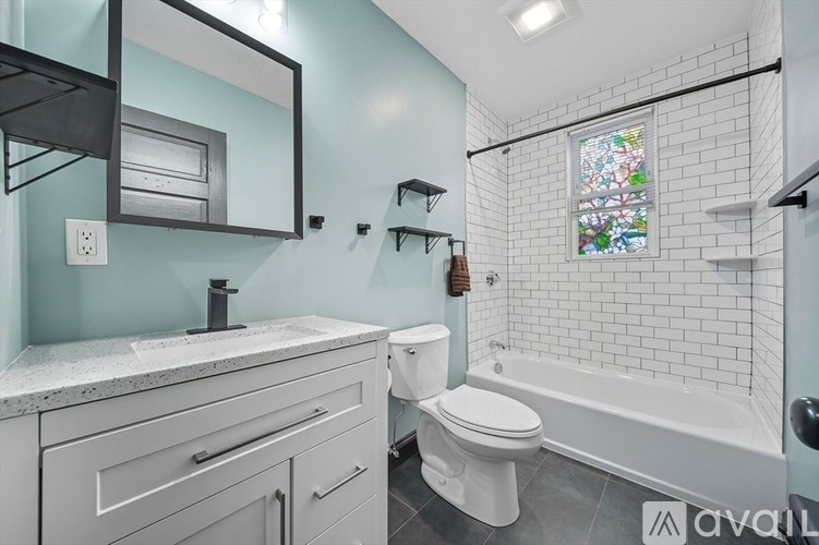 A bathroom with a toilet, sink, and a window with stained glass.