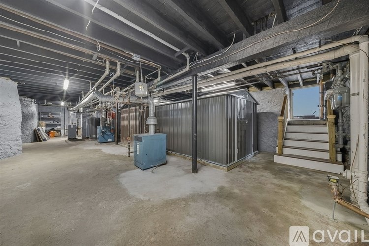 A large, empty industrial space with a concrete floor and exposed pipes on the ceiling.
