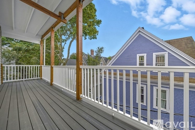 A blue house with a white railing and a wooden deck.