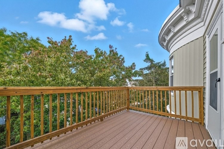 A wooden deck with a railing and a white house in the background.