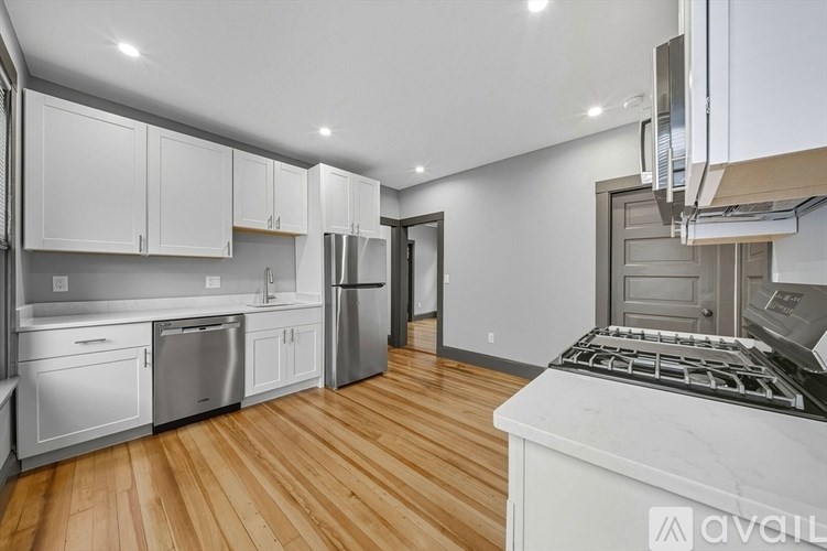 A kitchen with white cabinets and a wooden floor.