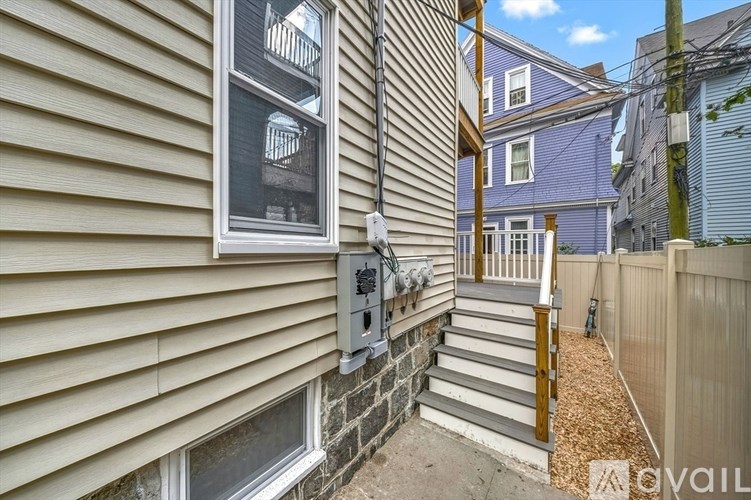 A house with a grey siding and a window with a view of a balcony.