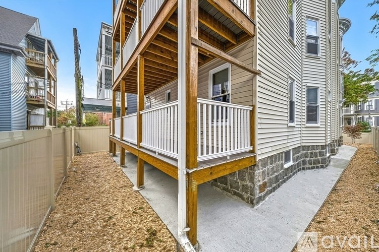 A modern two-story house with a wooden balcony and a stone wall.
