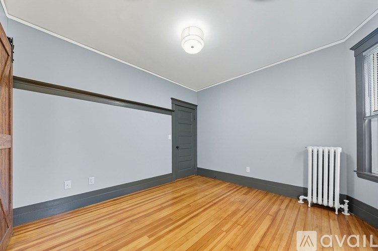 A room with wooden flooring and a white radiator.