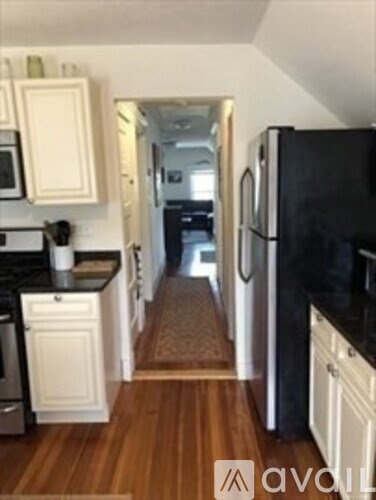 A kitchen with white cabinets and a black fridge.