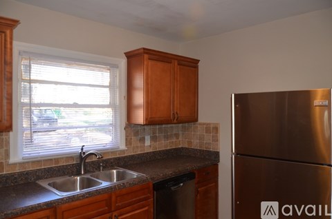 A kitchen with a stainless steel refrigerator and wooden cabinets.