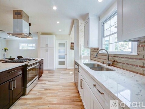 A kitchen with a white marble countertop and wooden flooring.