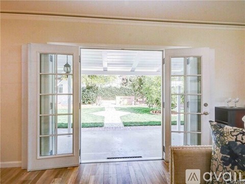 A living room with a couch and a view of a driveway through the open door.