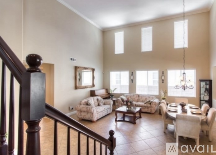 A living room with a staircase on the left and a dining area on the right.