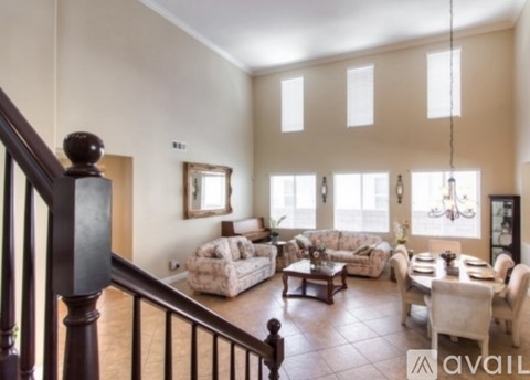 A living room with a staircase on the left and a dining area on the right.