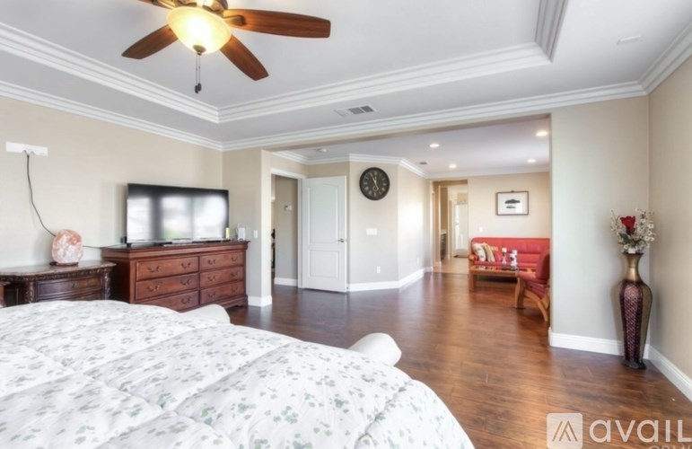 A bedroom with a large bed and a ceiling fan.