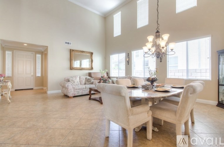 A dining room with a table set for six and a chandelier hanging from the ceiling.