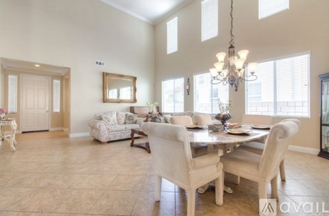 A dining room with a table set for six and a chandelier hanging from the ceiling.