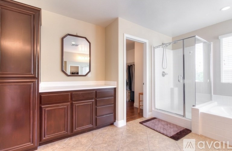 A bathroom with a brown cabinet, a mirror, and a glass shower stall.