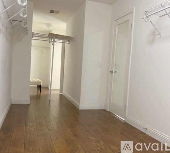 A room with wooden floors and white walls, with a chair and a table in the corner.