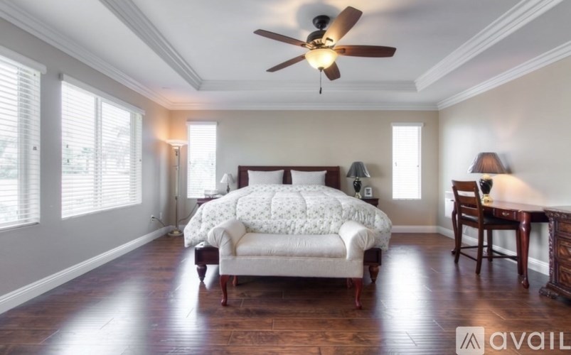 A bedroom with a bed, chair, and a ceiling fan.