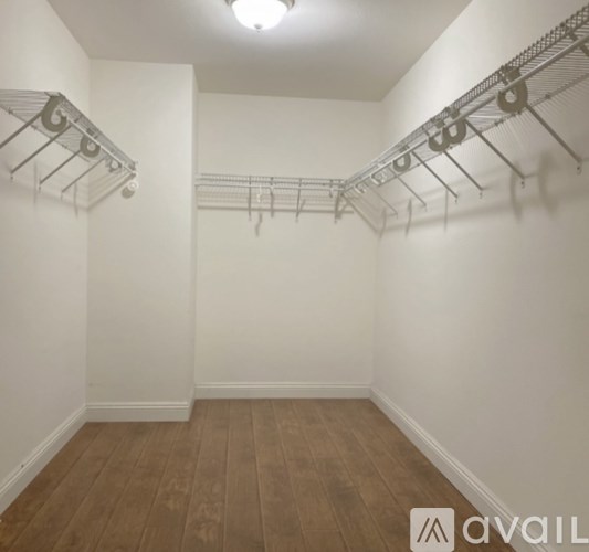 A room with a wooden floor and a wall-mounted rack with hooks.