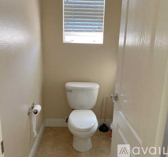 A white toilet in a small bathroom with a window.