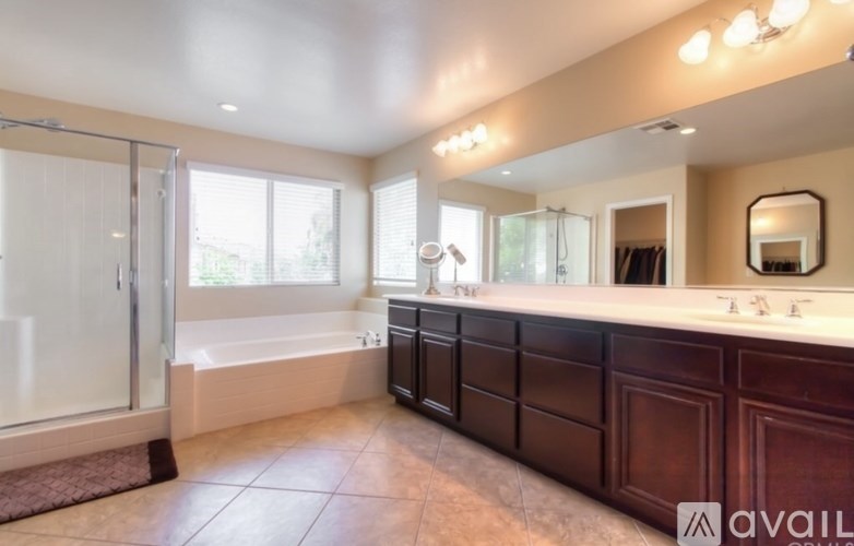 A bathroom with a large mirror, a bathtub, and a walk-in shower.