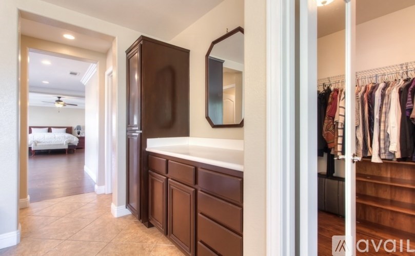 A hallway with a brown cabinet and a mirror on the wall.